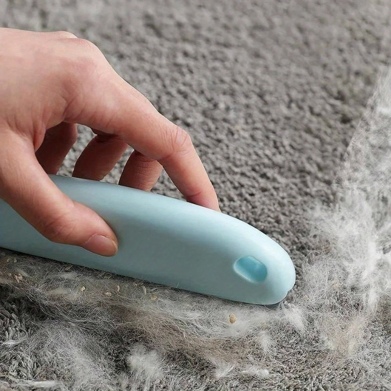 Light blue pet hair remover brush on gray carpet, lifting loose fibers