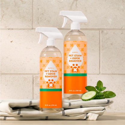 Two Pet Stain & Odor Remover spray bottles with cucumber-mint scent on towels