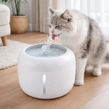 White pet water fountain on floor with cat drinking from the spout