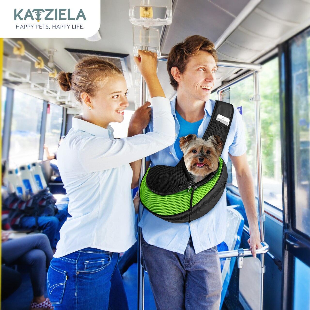 Green and black pet sling carrier worn on a dog while traveling in an indoor setting.