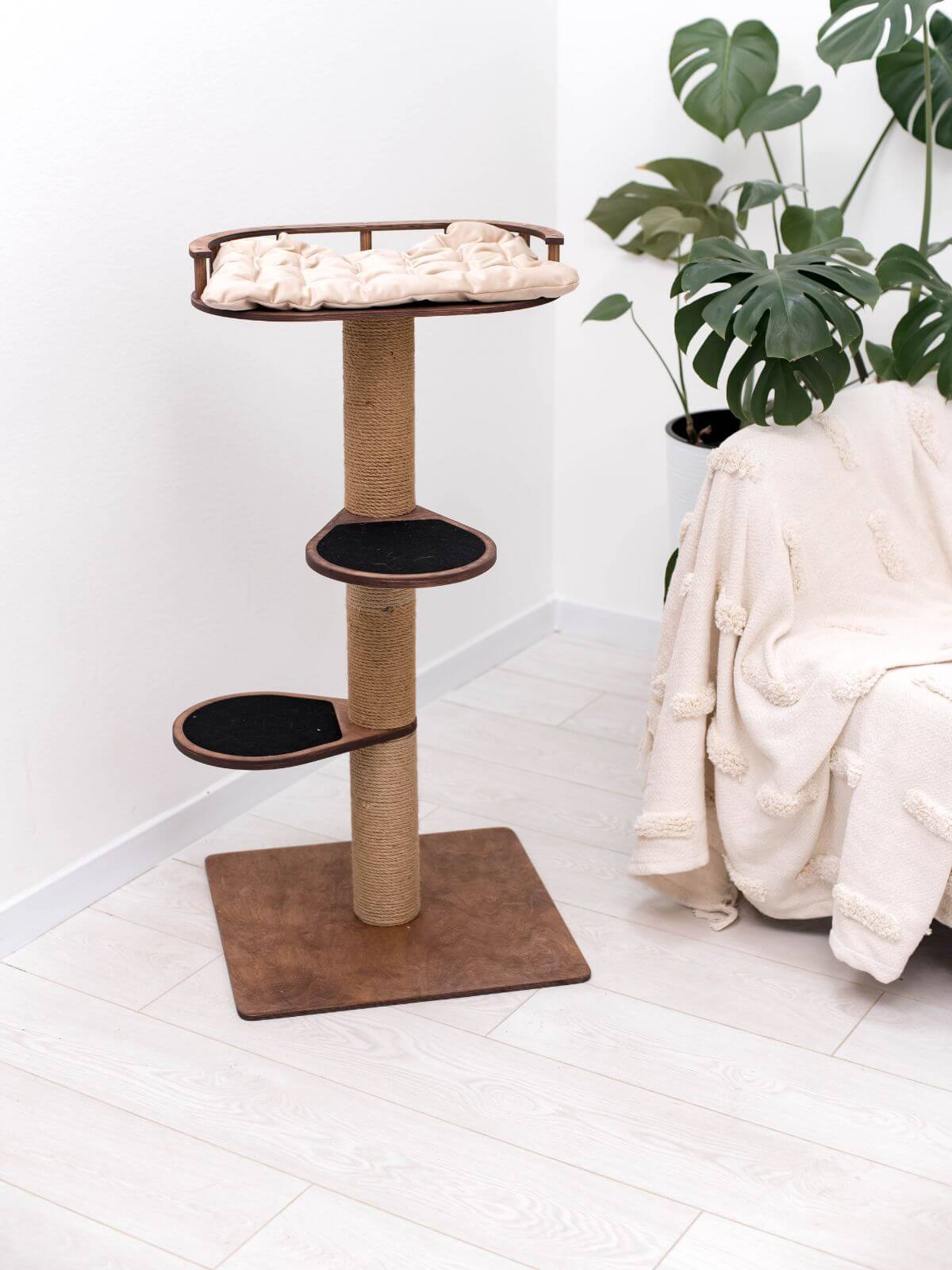 Small cat tree with cushioned top bed, two black round perches, sisal-wrapped post, base.